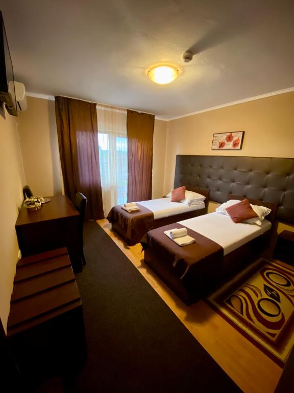 a hotel room with two beds and a desk at Hanul Lui Bogdan Economy INN in Făget
