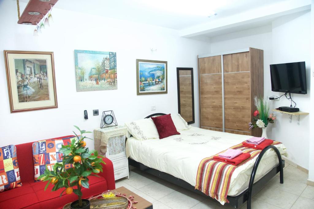 a bedroom with a bed and a couch and a tv at Country House in Beer Sheva