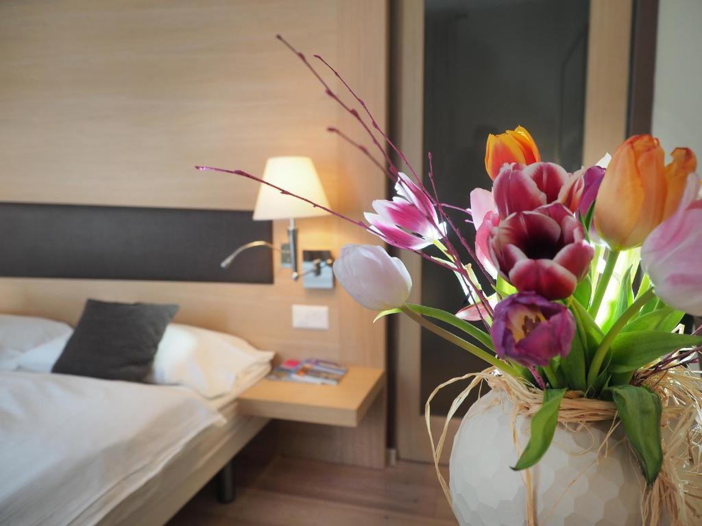 Ristorante Charme Hotel Tre Terre في Ponte Brolla: مزهرية مليئة بالورود الملونة في غرفة النوم