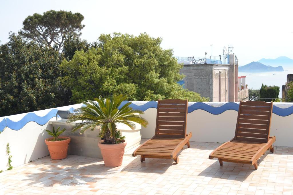 two wooden chairs sitting on a balcony with plants at Piccolo Tirreno Hotel Residence in Procida