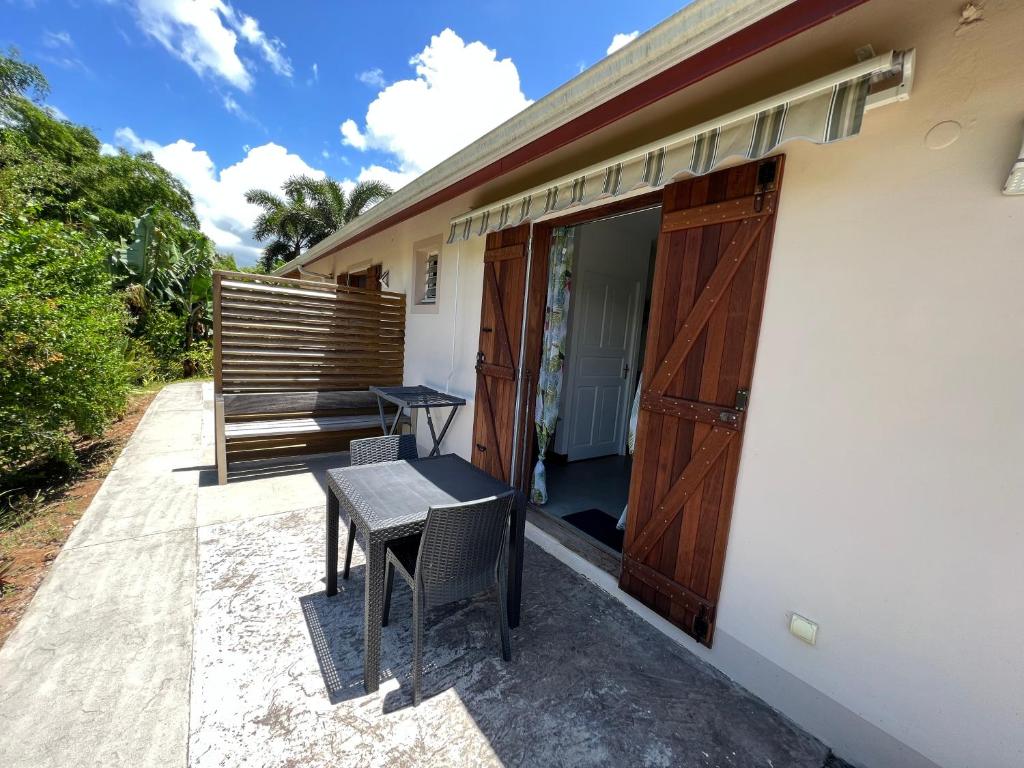 une terrasse avec une table et des chaises à côté d'une maison dans l'établissement Appartement Bois Banane, à Lamentin