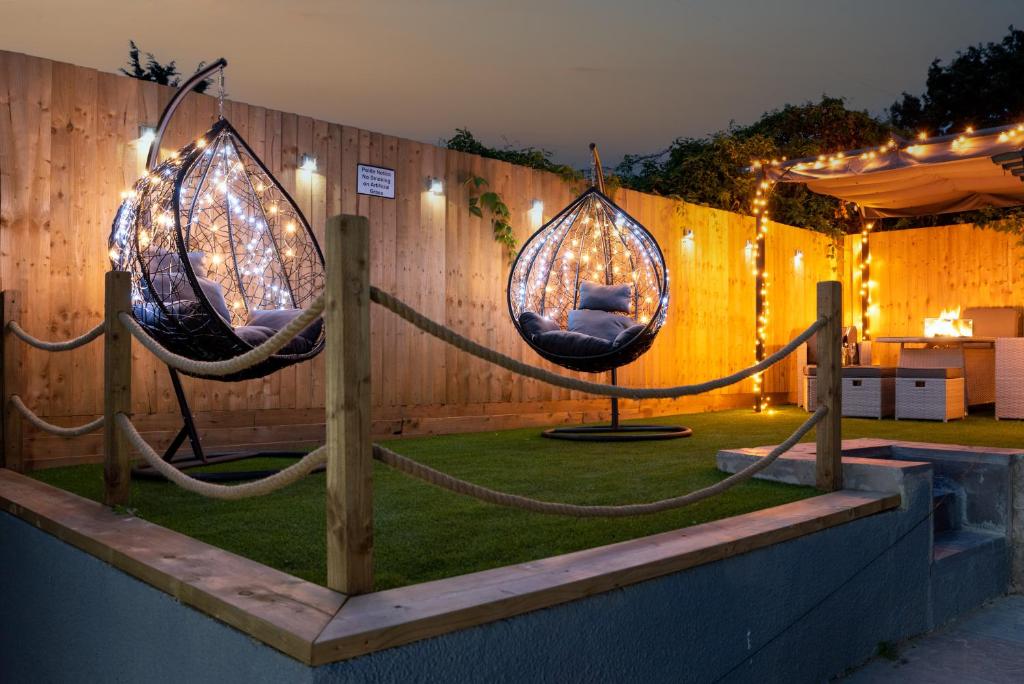 um jardim com dois baloiços numa cerca com luzes em Exquisite Cardiff Apartments- with Garden Lounge & Games Room em Cardiff
