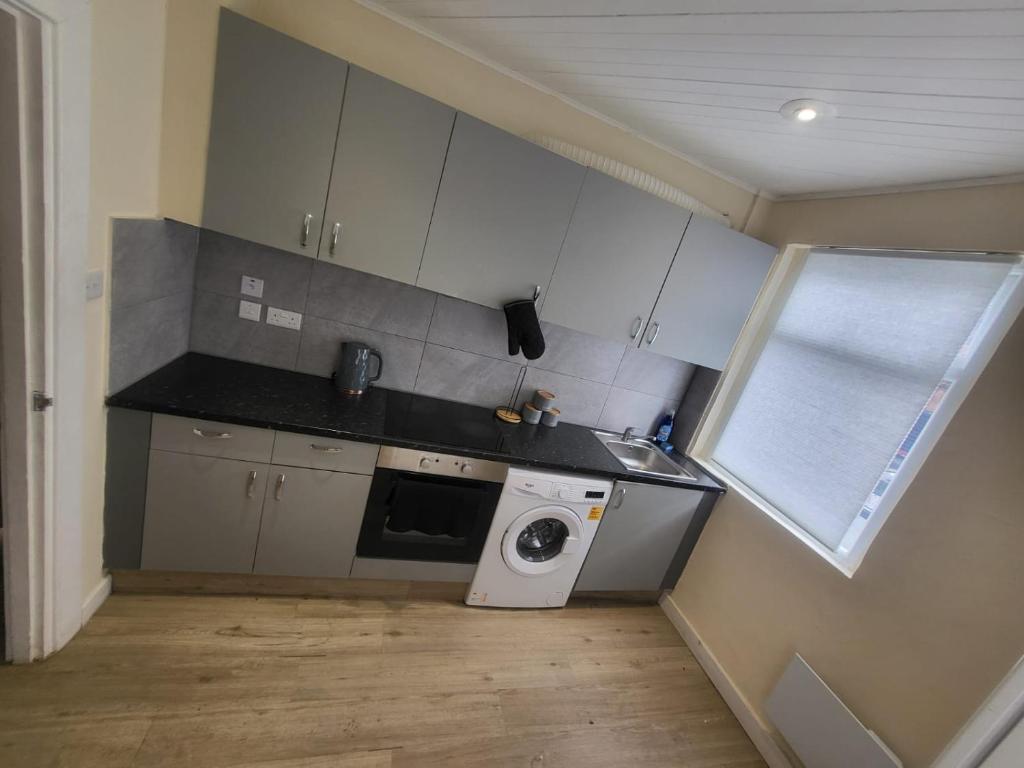 a small kitchen with a washing machine and a sink at Beautiful 2-bed flat in the heart of Hendon in The Hyde