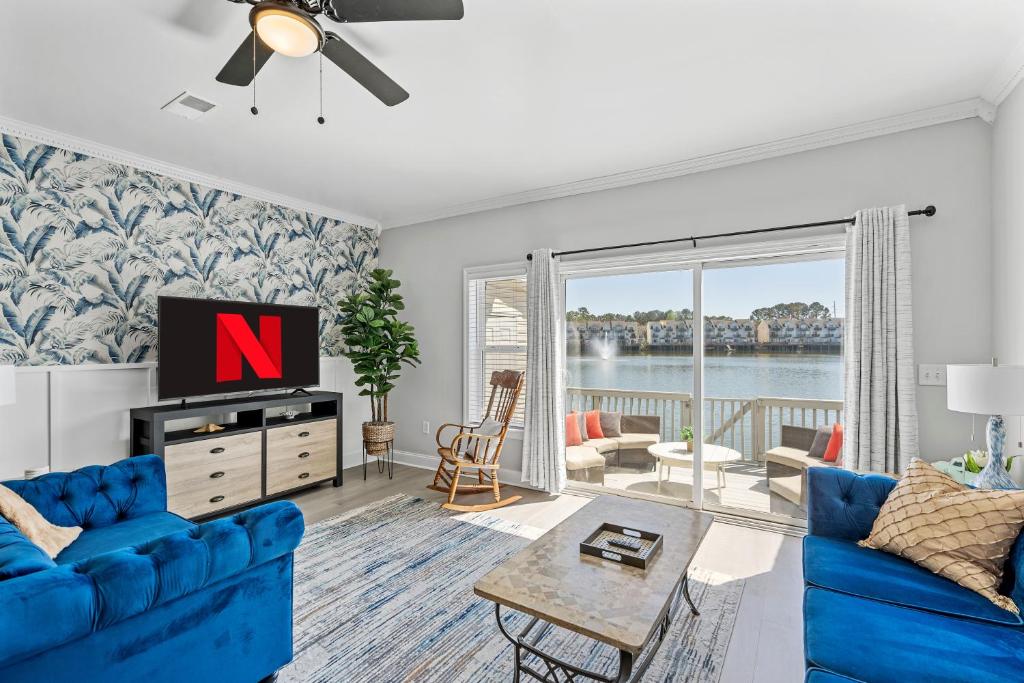 a living room with a blue couch and a tv at ☆Live on the Water! Lake Palmetto Palm w/ Patio - 10Min to Downtown & Beaches☆ in Charleston