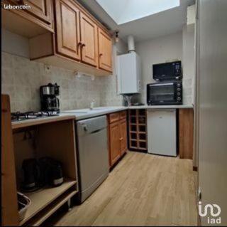 - une petite cuisine avec des armoires et des appareils en bois dans l'établissement Les Falaises d'Etretat, à Étretat