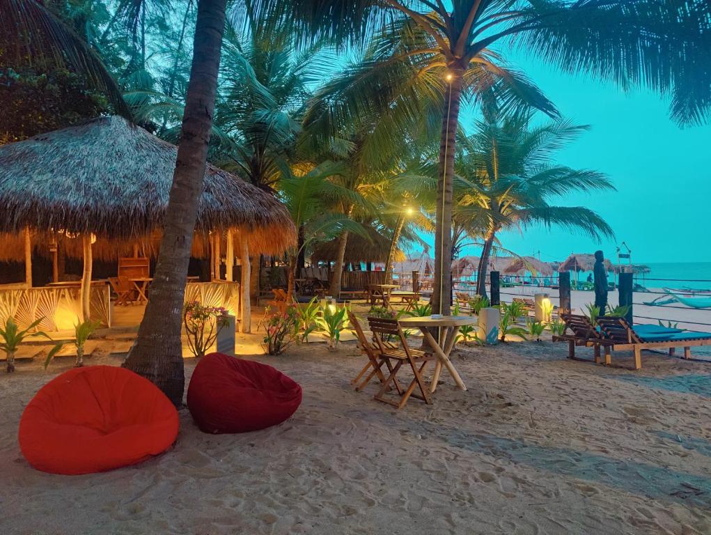 plaży z krzesłami, stołami i palmami w obiekcie Atteriya CHILL w mieście Arugam Bay