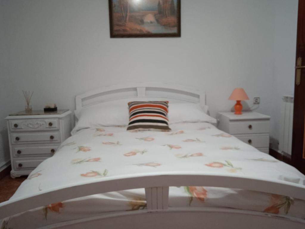 ein Schlafzimmer mit einem weißen Bett und zwei Nachttischen in der Unterkunft El patio de Marcos in La Recueja
