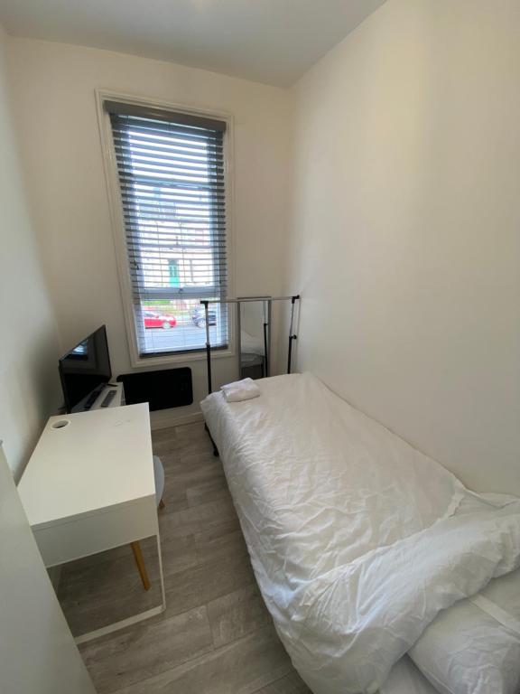 1 dormitorio con cama, mesa y ventana en Small Single room walking distance to Hove Station, en Brighton & Hove