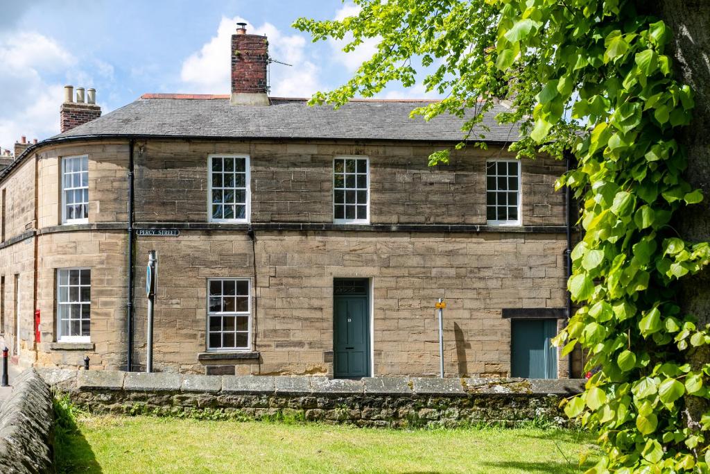 an old stone house with a green door at Algernon House in Alnwick