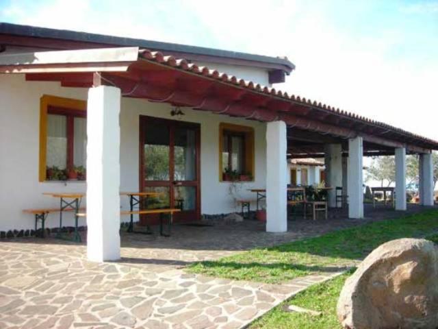 a building with a patio with tables and a roof at Agriturismo Su Nuratolu in Sagama