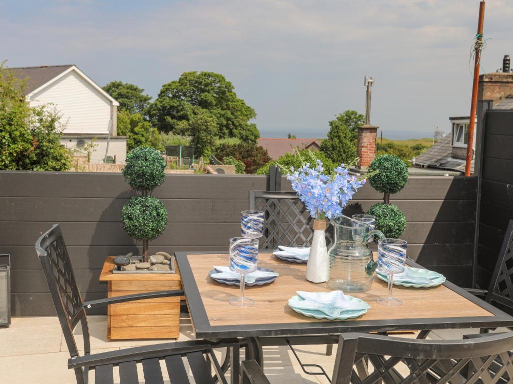 a wooden table with chairs and blue flowers on a patio at Brigwyn in Pwllheli