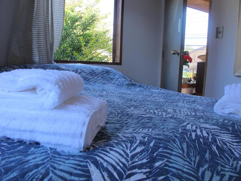 un letto con piumone blu e bianco e una finestra di Hostal Centro Pucón B a Pucón