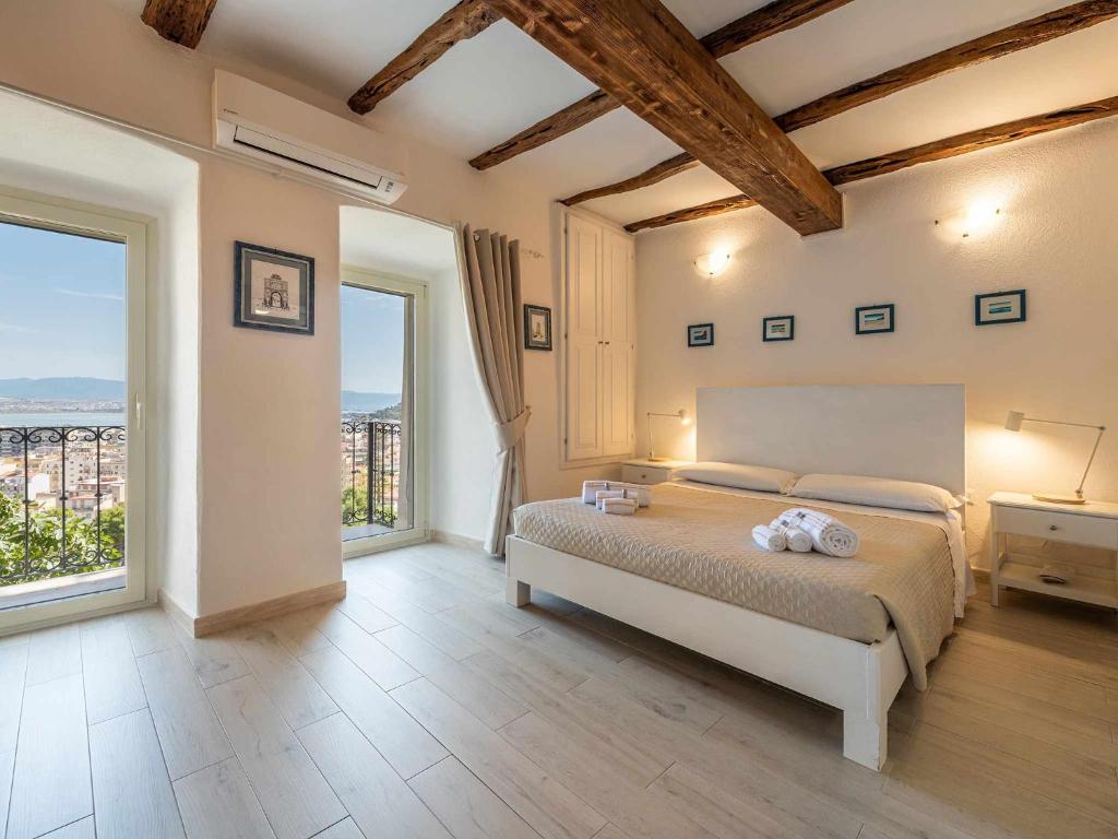 ein Schlafzimmer mit einem großen Bett und großen Fenstern in der Unterkunft Karalis Relais Appartamento privato con Jacuzzi in Cagliari