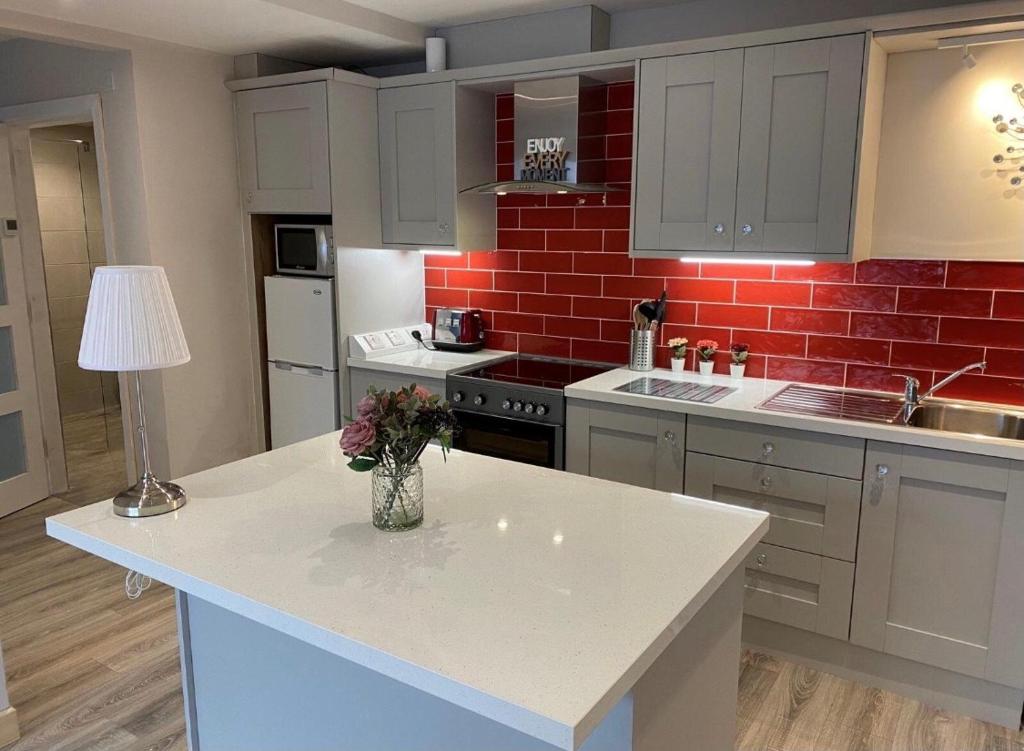 a kitchen with a white counter and a red brick wall at Trinity Apartments Four 1-Bedroom Apts Waterford City Centre in Waterford