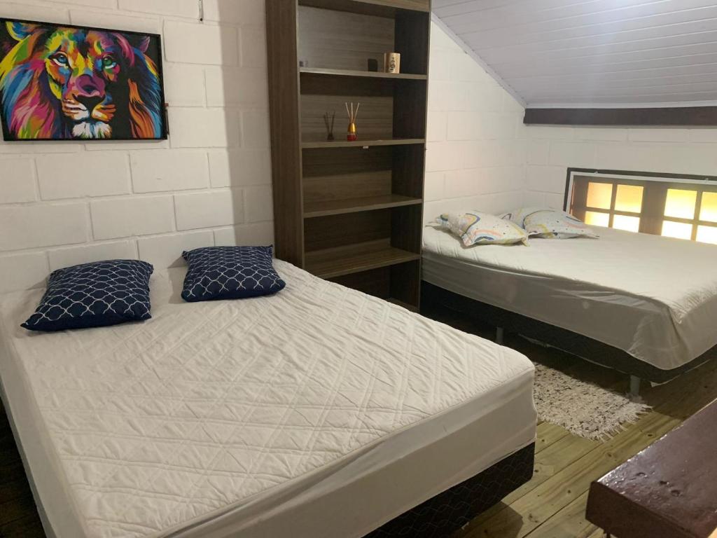 een kamer met 2 bedden en een schilderij aan de muur bij CHALÉ LAZER COMPLETO 700mts PRAIA in Ubatuba