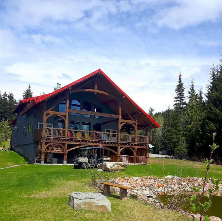 una gran casa de madera con una gran terraza en un campo en Heather Mountain Lodge, en Golden