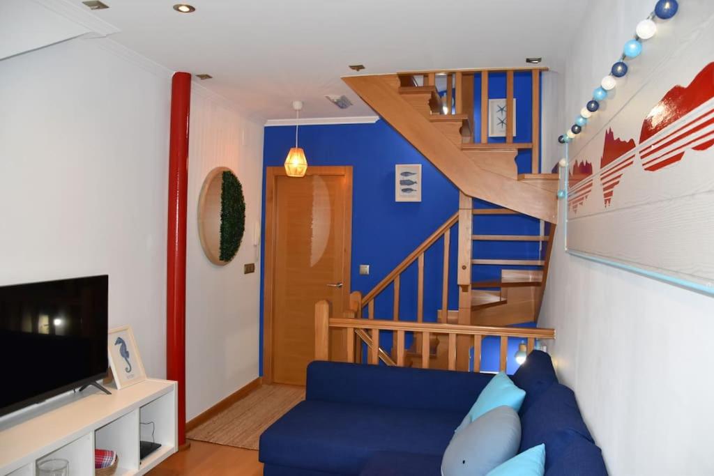 a living room with a blue couch and a staircase at Casa Punta Balea, en el centro in Cangas de Morrazo