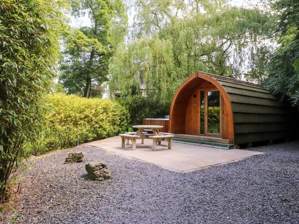 a wooden shelter with a picnic table in a garden at Homewood Pod in Preston