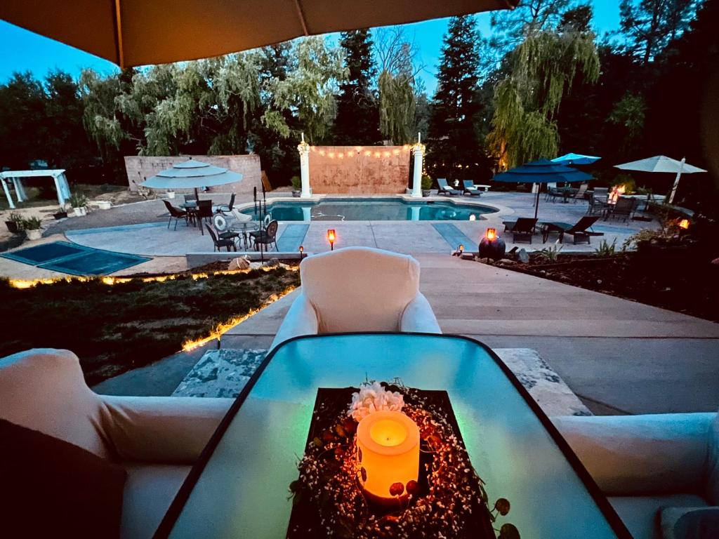 una mesa de cristal con una vela junto a una piscina en The Oasis en Redding