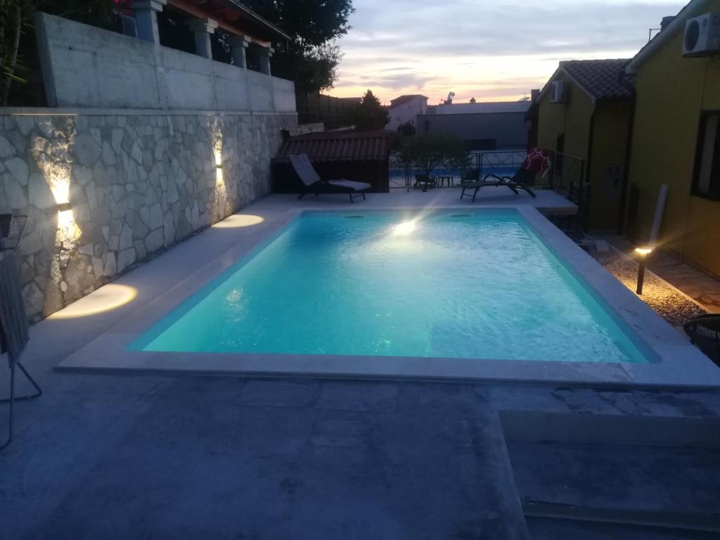 una piscina en un patio trasero al atardecer en KAMENJAK VOLME, Cousy house with Pool en Banjole