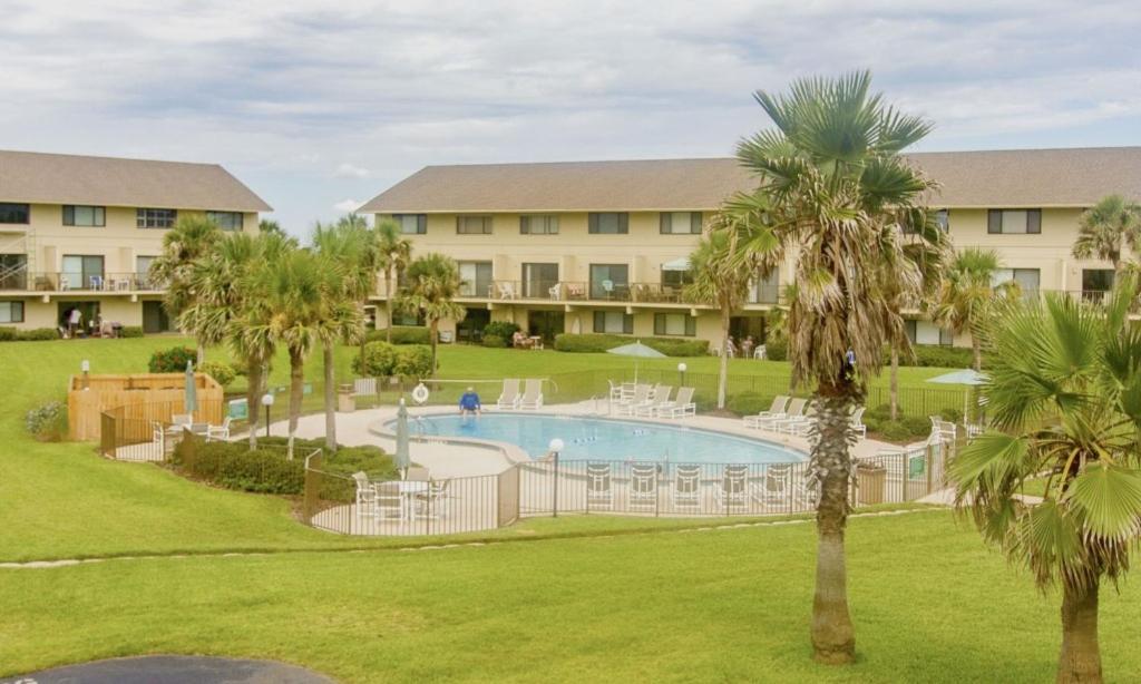 a resort with a pool and chairs and palm trees at Summerhouse 228 in Saint Augustine