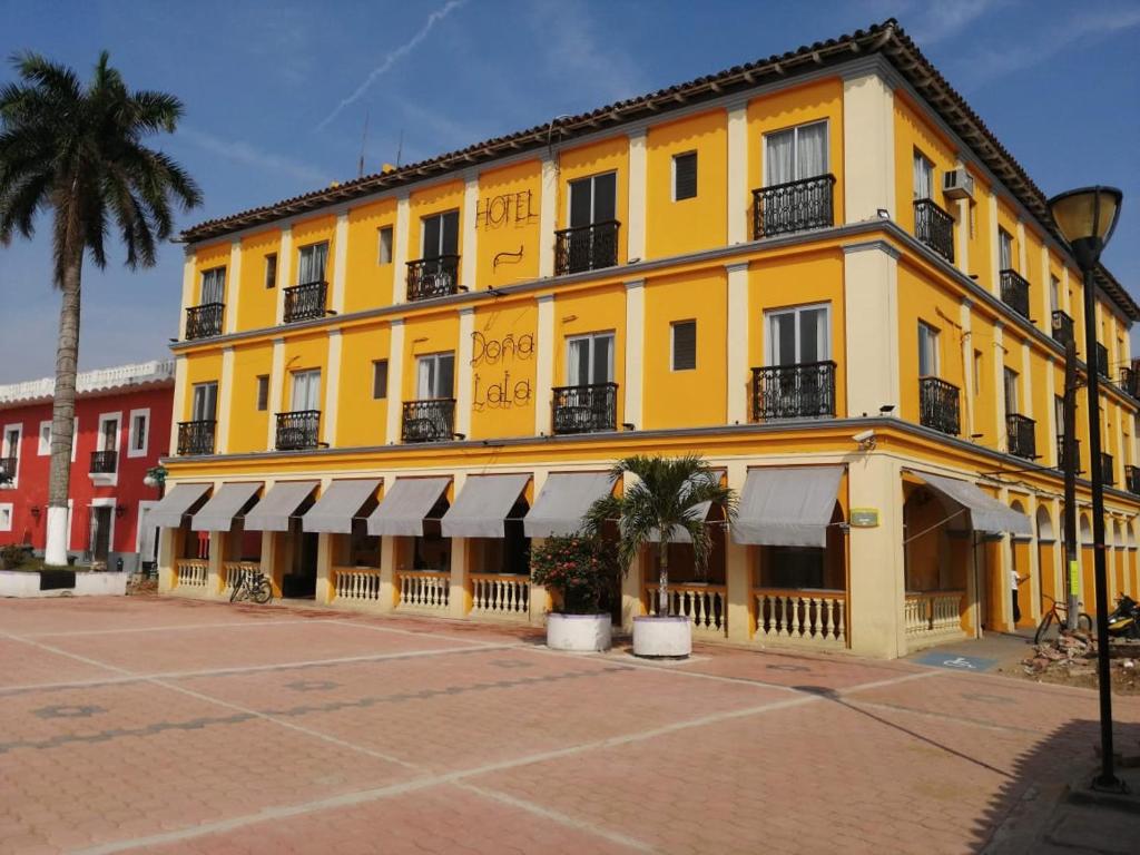 a yellow building with palm trees in front of it at Hotel Posada Doña Lala in Tlacotalpan