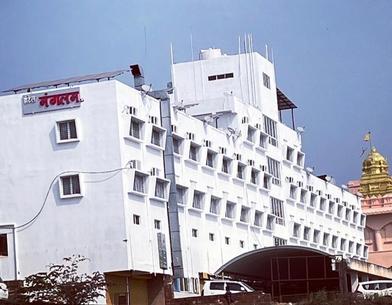 een groot wit gebouw met een bord erop bij Hotel Mangalam in Kurandvād