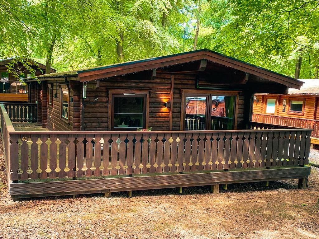 a wooden cabin with a fence in front of it at Leafy Hollow Lodge in Louth