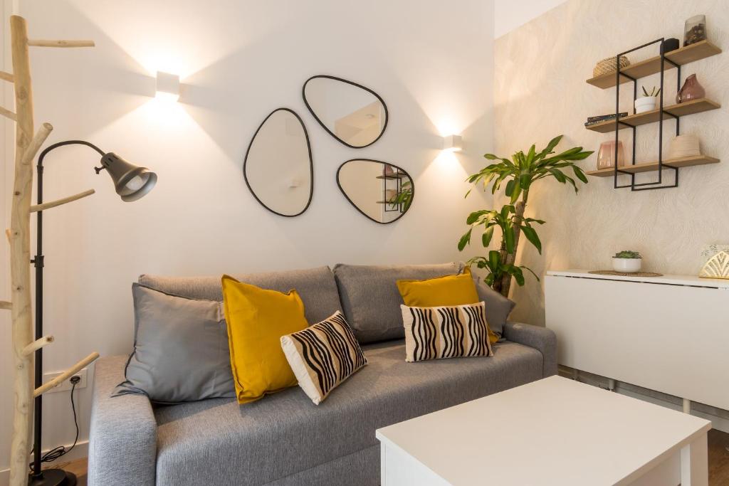 uma sala de estar com um sofá cinzento com almofadas amarelas em Modern and cozy- 1 Bedroom 1 Bathroom -Lavapiés em Madri