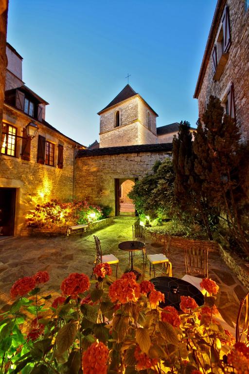 a courtyard with a building with a table and flowers at Château Hôtel La Terrasse - Teritoria in Meyronne