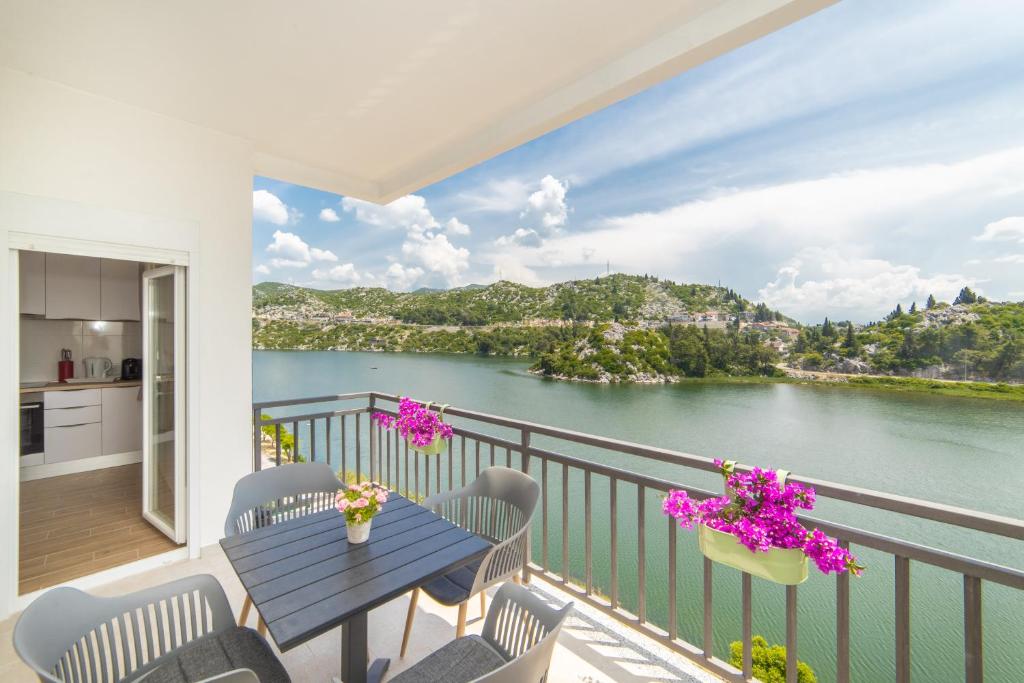 balcón con mesa, sillas y vistas al agua en Lakeview Apartments en Ploče