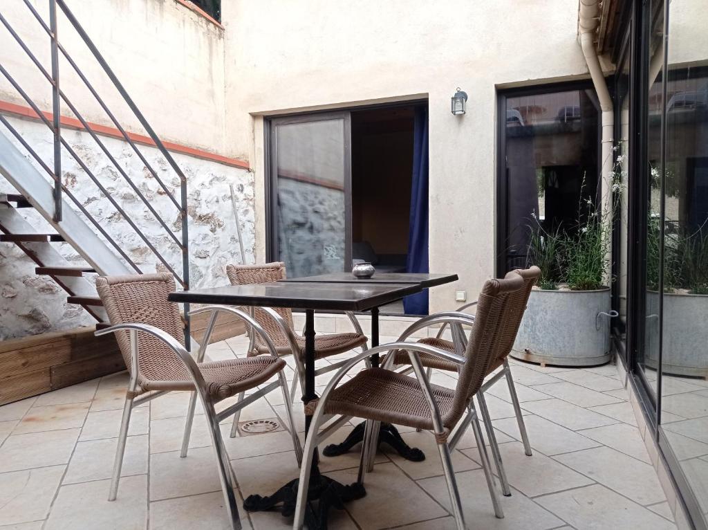 une table noire et des chaises sur une terrasse dans l'établissement Maison de charme avec patio et terrasse de toit, à Estagel