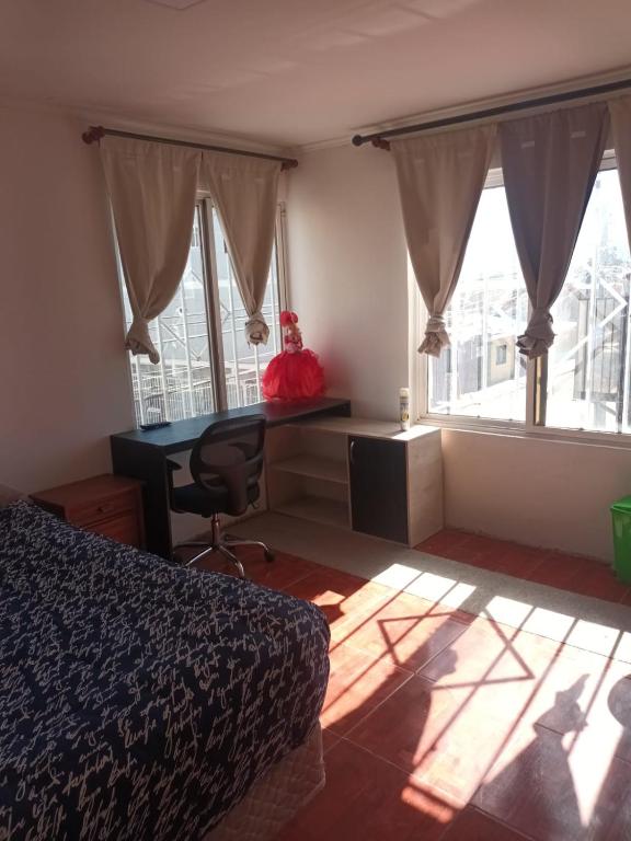 a bedroom with a bed and a desk and windows at Casa R in Calama