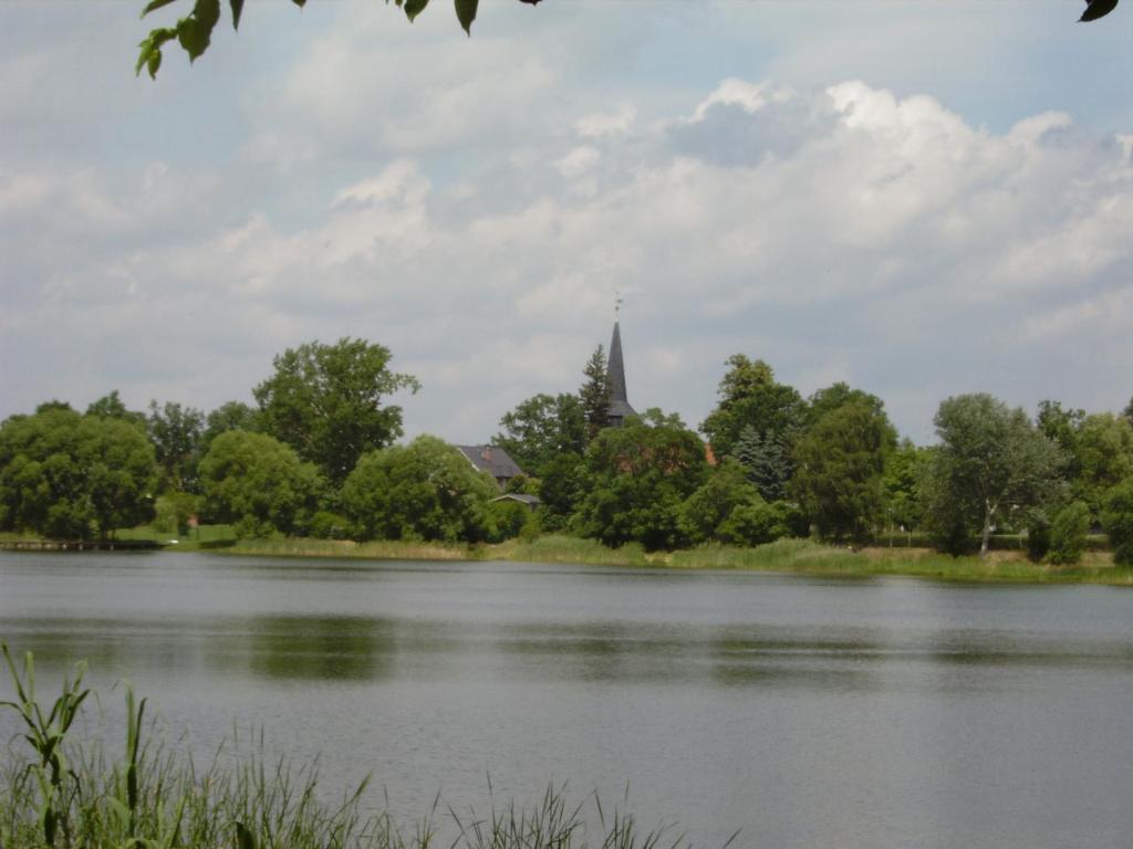 a view of a lake with a church in the background at Ferienwohnung Last in Kyritz