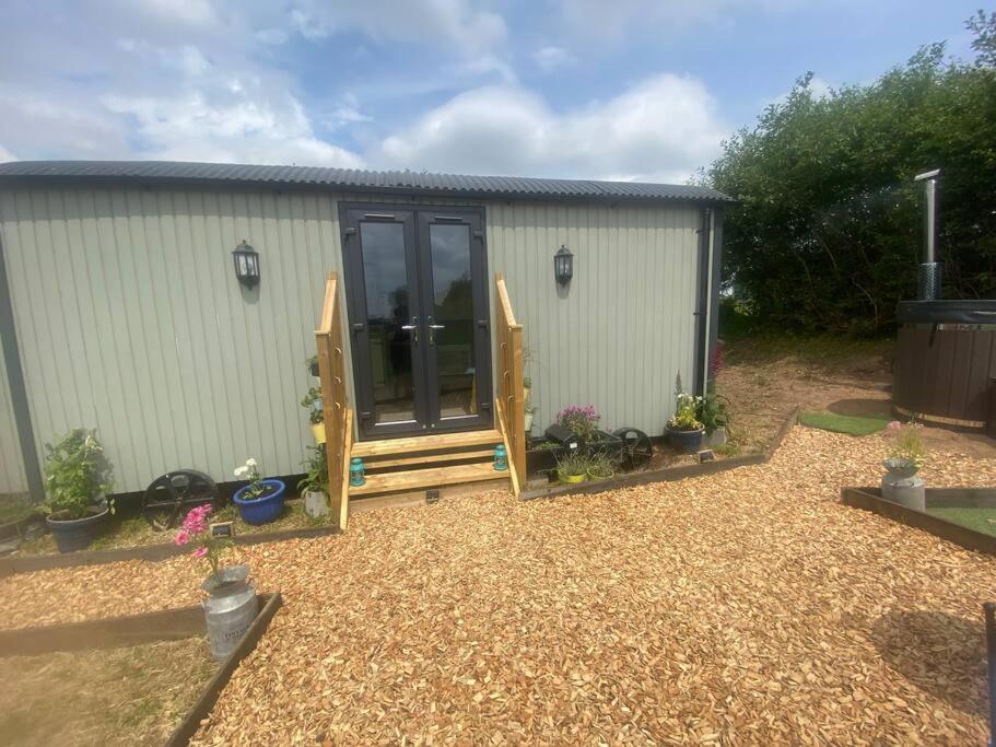 a small shed with a door and a patio at Close to Nature Easy to Find shepherd's hut in North Molton