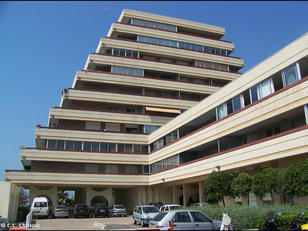 duży budynek z samochodami zaparkowanymi przed nim w obiekcie Joli 3 Pièces rénové avec terrasse, vue mer et ascenseur - FR-1-716-2 w mieście La Grande-Motte