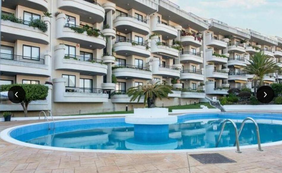 un hotel con piscina frente a un edificio en Estupendo apartamento en San Vicente do Mar O Grove, en San Vicente do Mar