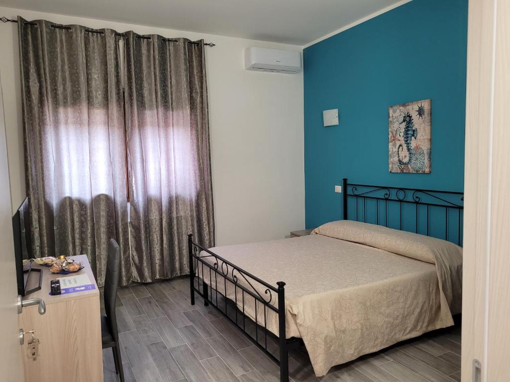 1 dormitorio con cama y pared azul en Rooms da Pisicchio, en Fiumicino