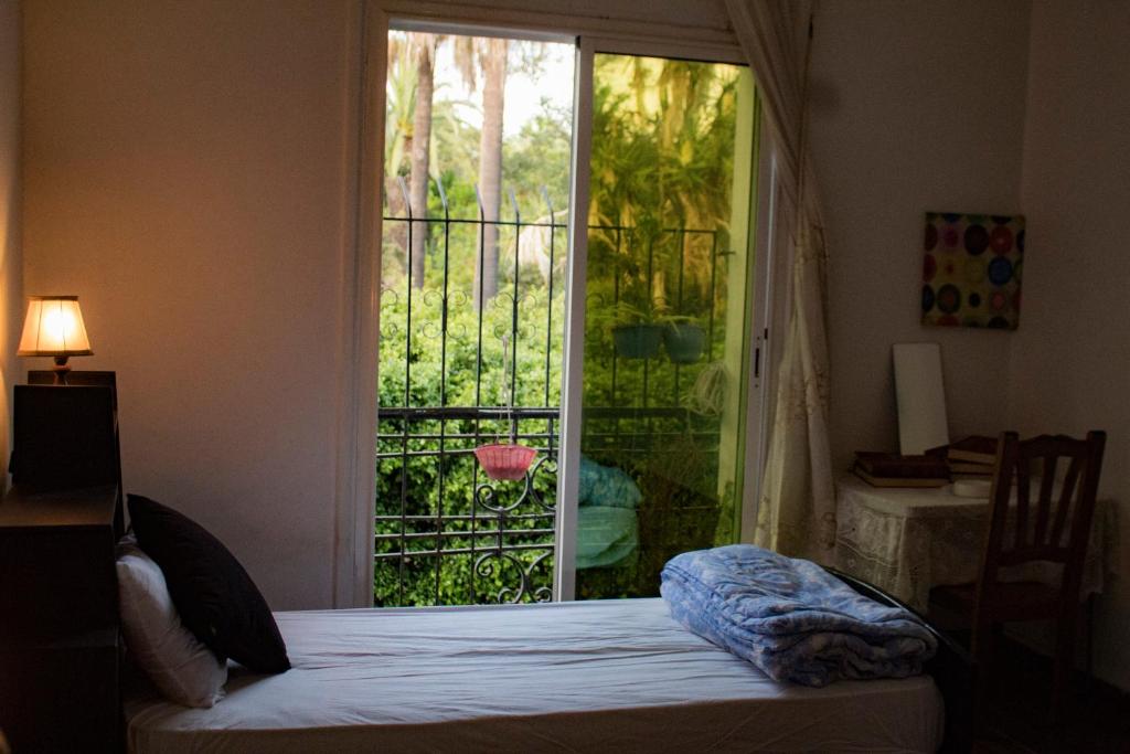 a bedroom with a bed and a large window at Chambre du jardin in Rabat