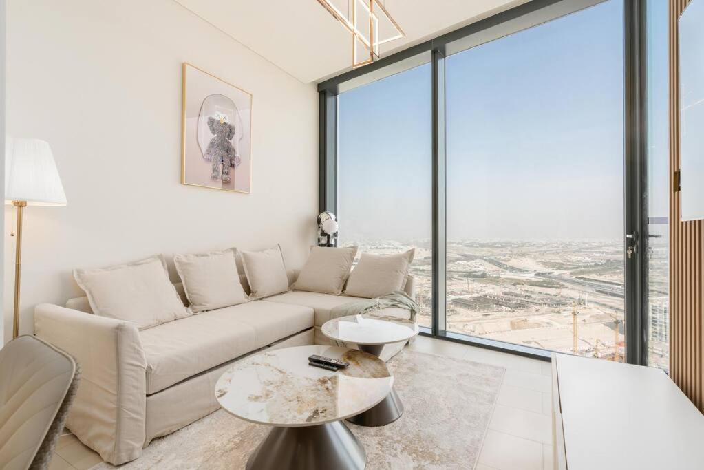 een woonkamer met een bank en een groot raam bij Modern 1bdr - 10min from Burj Khalifa - Sobha Waves in Dubai