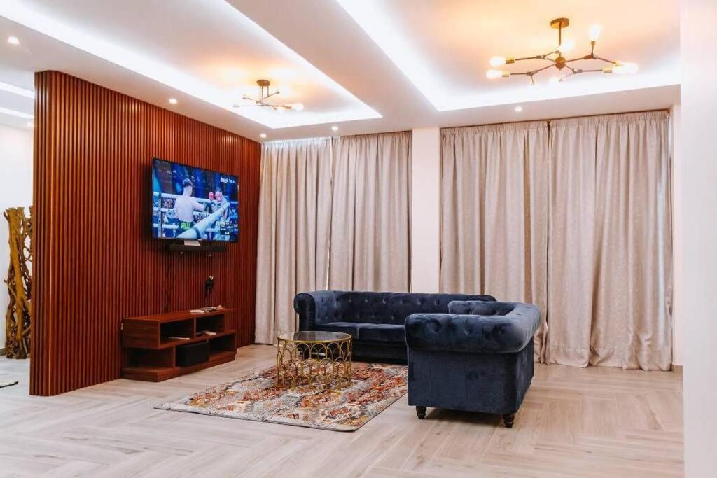 Giani Lodge في لوميه: غرفة معيشة مع أريكة وتلفزيون على الحائط