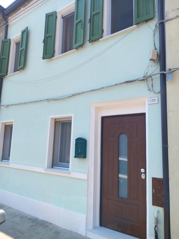 un edificio con porta marrone e finestre verdi di IL GRANCHIO BLU a Comacchio