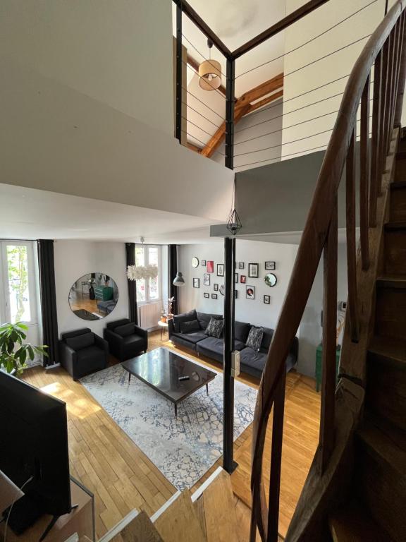 sala de estar con escalera y sofá en Duplex de charme en centre ville avec terrasse en Brive-la-Gaillarde