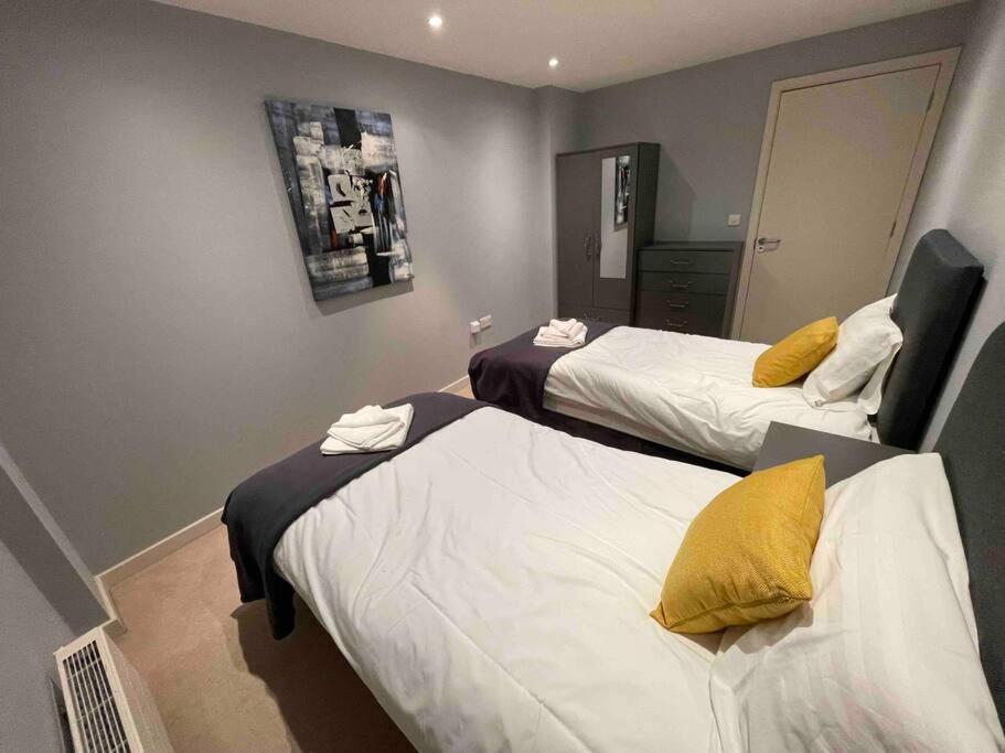 a hotel room with two beds with yellow pillows at 2 Bedroom Flat in Bedford