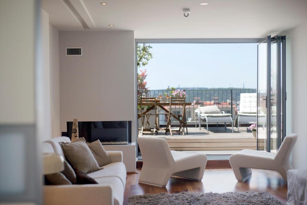 a living room with white furniture and a view of a patio at Luxury Penthouse Apartment in Prague