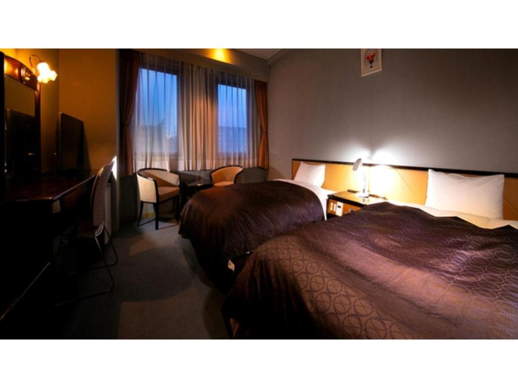 pokój hotelowy z 2 łóżkami, stołem i krzesłami w obiekcie Hotel Satsukien - Vacation STAY 75959v w mieście Kanoya