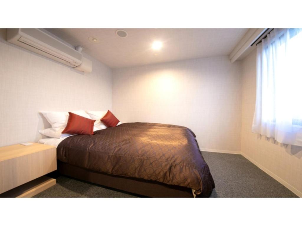 - une chambre avec un lit doté d'oreillers rouges et une fenêtre dans l'établissement Hotel Satsukien - Vacation STAY 75958v, à Kanoya
