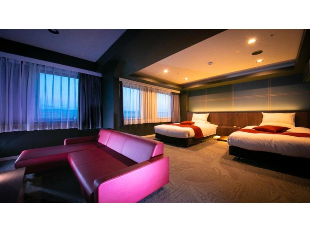 a hotel room with two beds and a purple couch at Hotel Satsukien - Vacation STAY 75962v in Kanoya