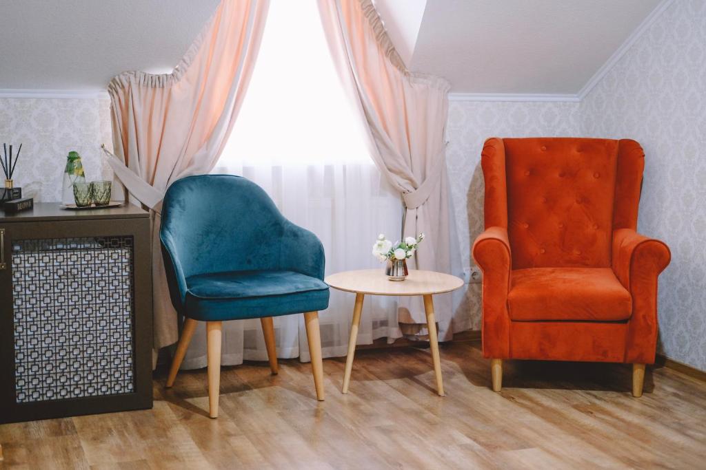 文尼察的住宿－Hotel DENINNA，客厅配有两把椅子和一张桌子