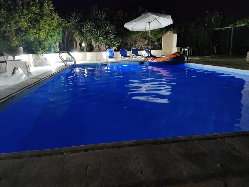 uma grande piscina azul com cadeiras e um guarda-sol em فيلا برايفت بول في مارينا الساحل الشمالي em El Alamein